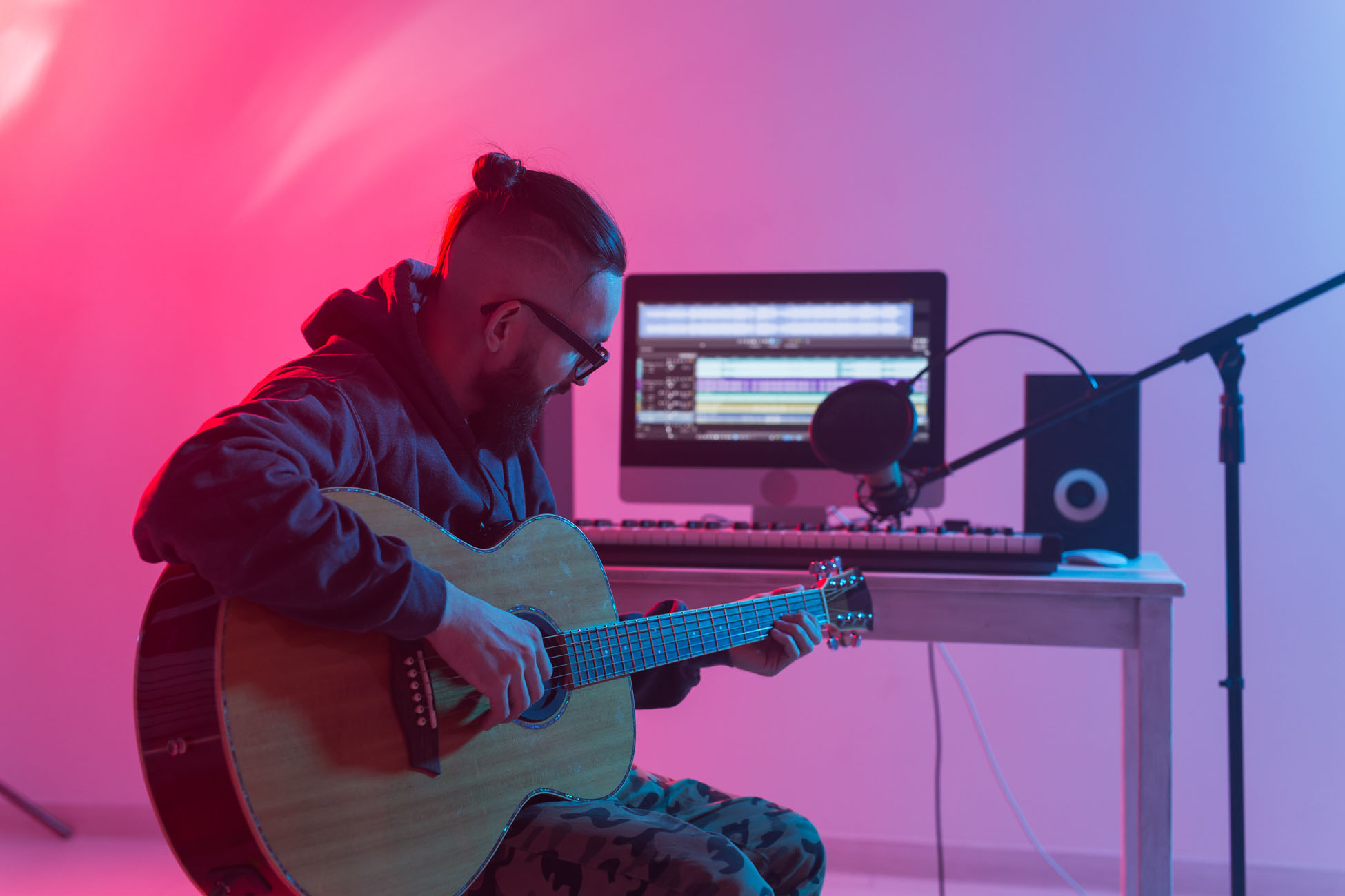 Create music and a recording studio concept - Bearded man guitarist recording electric guitar track in home studio.